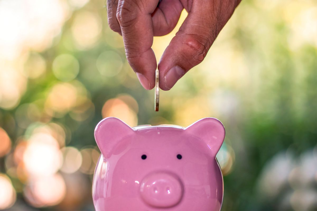 piggy bank savings hand Mackay Financial Planner's hand putting a coin into a piggy bank