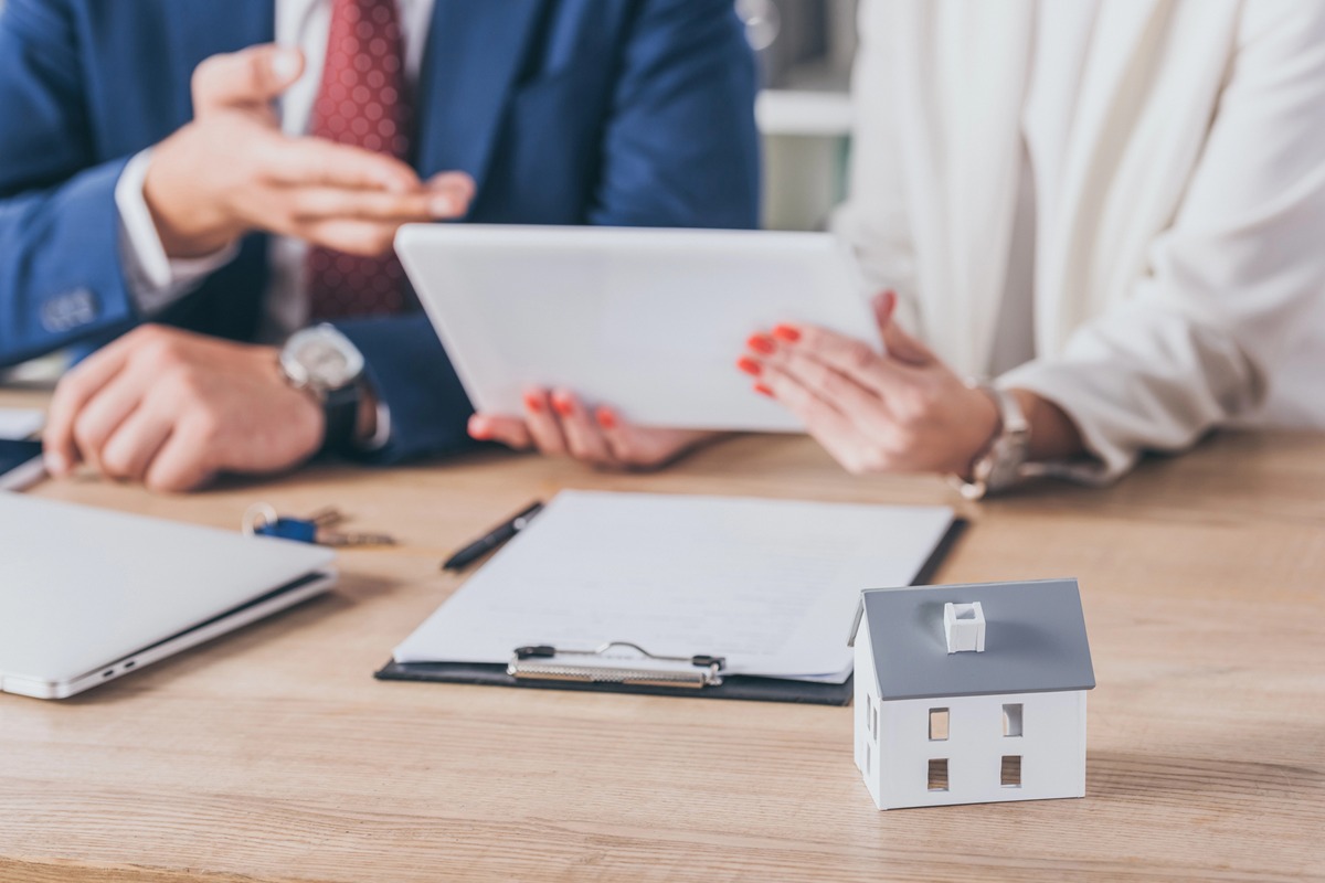 Why Your Borrowing Capacity Can Change Even if Your Income Hasn’t a client and a real estate agent discuss home buying, with paperwork and a house model on the table