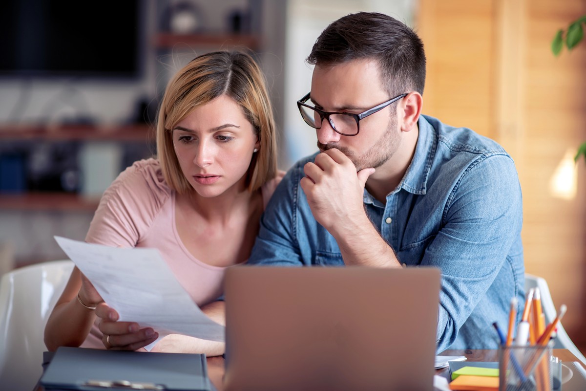 The Hidden Cost of Extending Your Mortgage Back to 30 Years family managing budget, reviewing their bank accounts using laptop in kitchen
